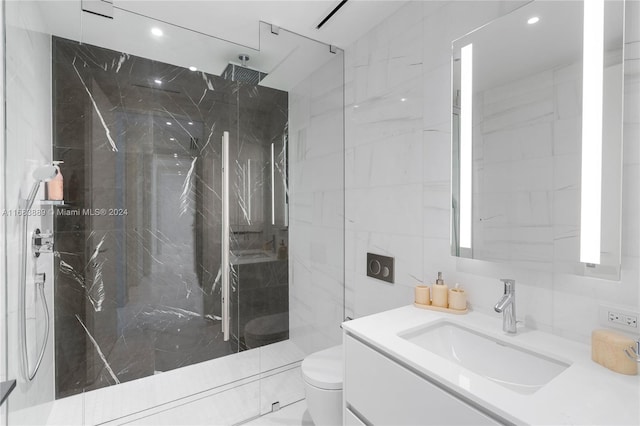 bathroom featuring a tile shower, vanity, toilet, and tile walls