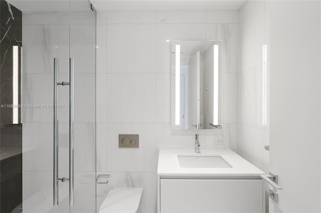 bathroom with vanity, walk in shower, toilet, and tile walls