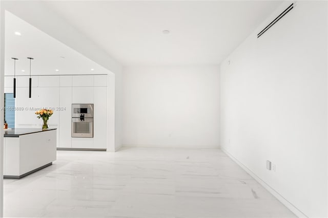 interior space with stainless steel double oven, white cabinetry, and hanging light fixtures