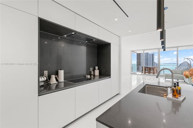 kitchen featuring sink, white cabinets, backsplash, and black electric cooktop