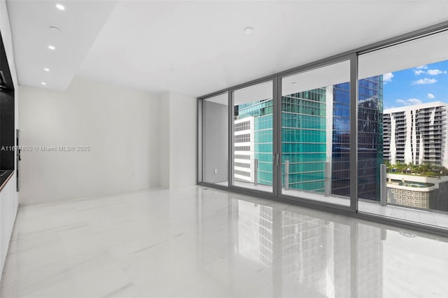 unfurnished room with marble finish floor, floor to ceiling windows, a city view, and recessed lighting