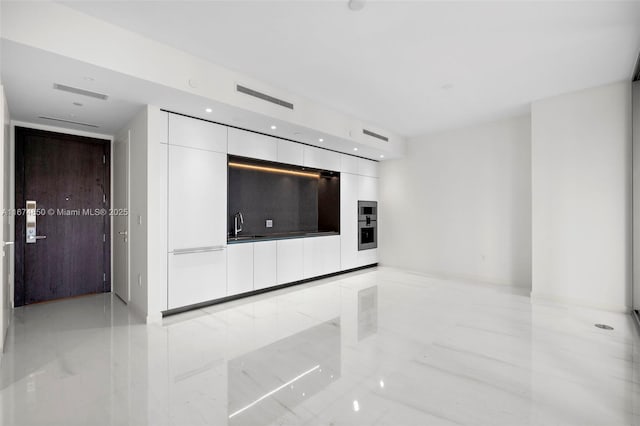 unfurnished living room with marble finish floor, visible vents, and a sink