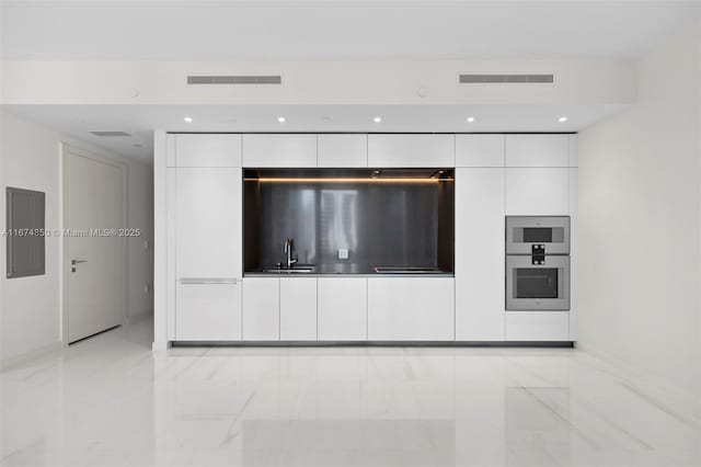 kitchen with a sink, visible vents, white cabinets, marble finish floor, and modern cabinets