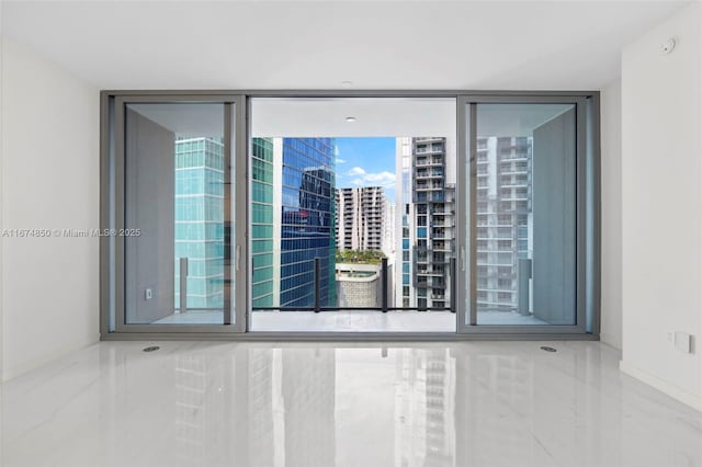 empty room featuring marble finish floor, a view of city, and baseboards