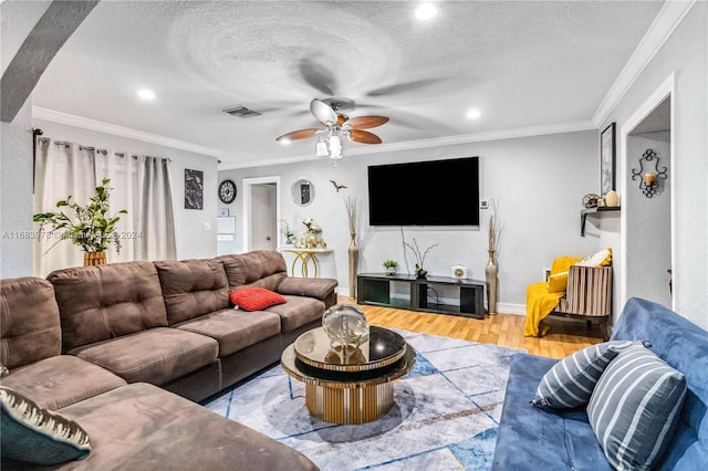 living room featuring ceiling fan, a textured ceiling, ornamental molding, and light hardwood / wood-style flooring