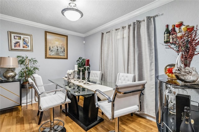 dining space with hardwood / wood-style floors, crown molding, and a textured ceiling