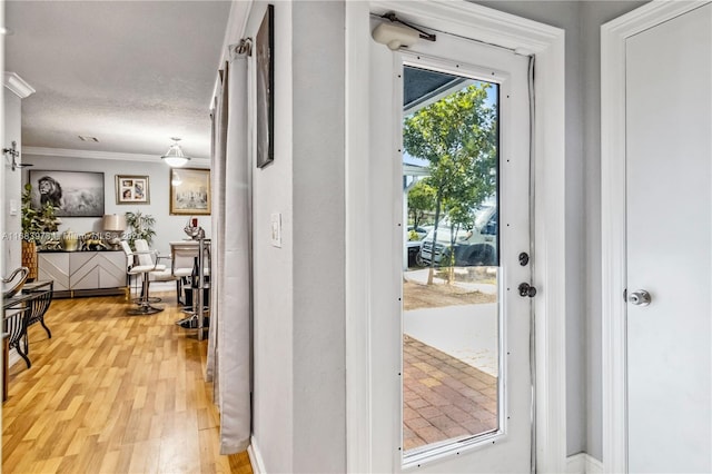 doorway to outside featuring crown molding, a textured ceiling, and hardwood / wood-style flooring