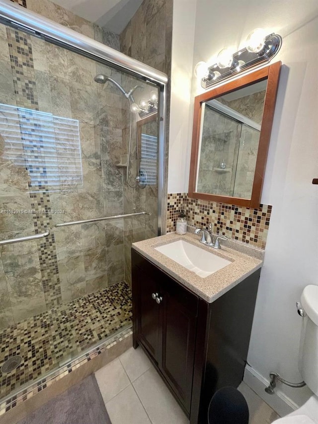 bathroom with vanity, toilet, a shower with shower door, and backsplash