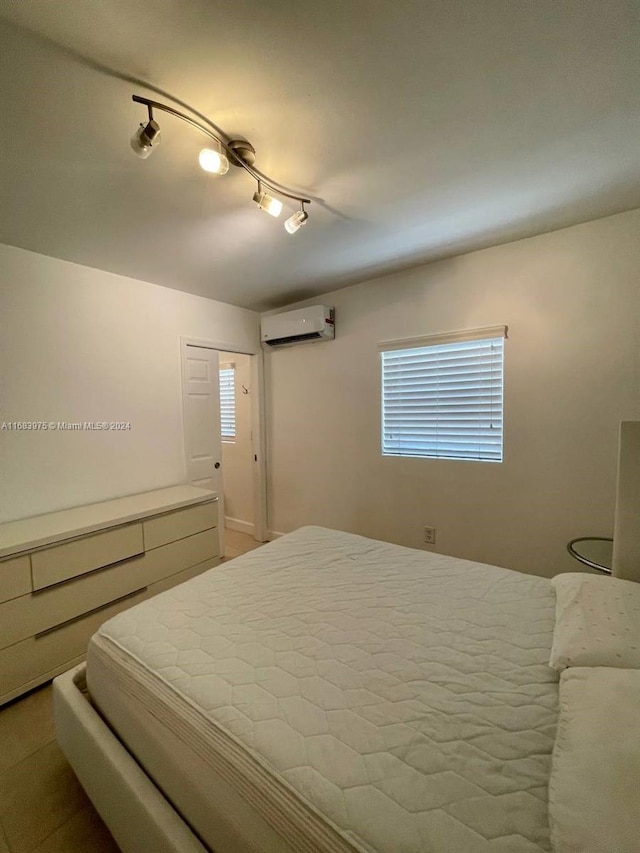 bedroom featuring rail lighting and an AC wall unit