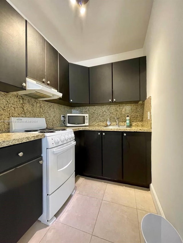 kitchen with white appliances, backsplash, dark brown cabinets, light stone counters, and light tile patterned floors