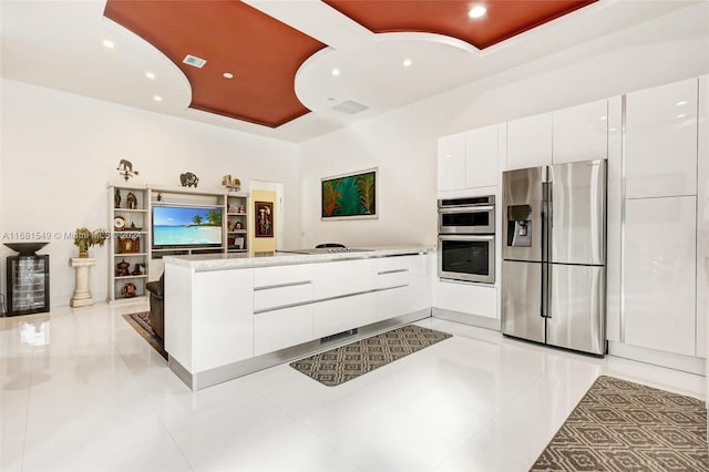 kitchen featuring white cabinetry, kitchen peninsula, stainless steel appliances, and a tray ceiling