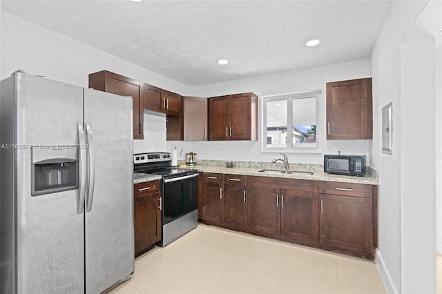 kitchen featuring sink, appliances with stainless steel finishes, light stone counters, and dark brown cabinets