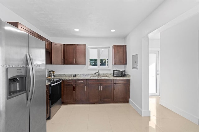 kitchen featuring appliances with stainless steel finishes, sink, dark brown cabinets, light stone counters, and light tile patterned floors