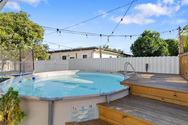 view of swimming pool with a wooden deck and a trampoline