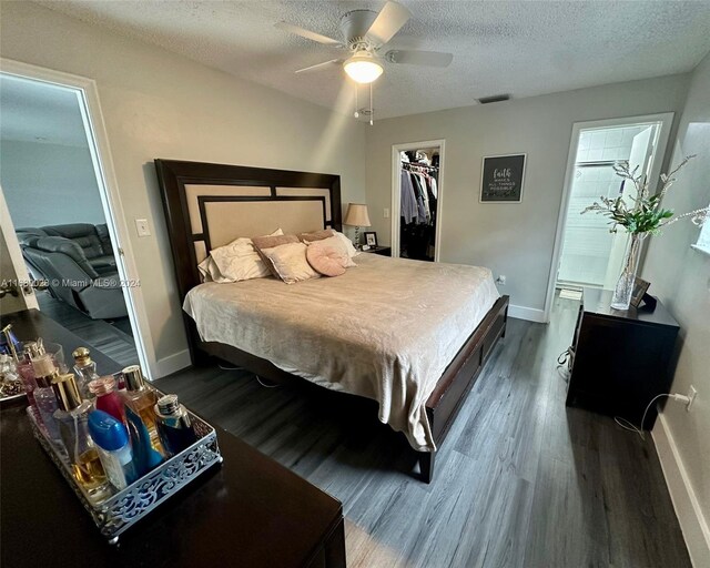 bedroom with a spacious closet, dark hardwood / wood-style flooring, ceiling fan, and a textured ceiling