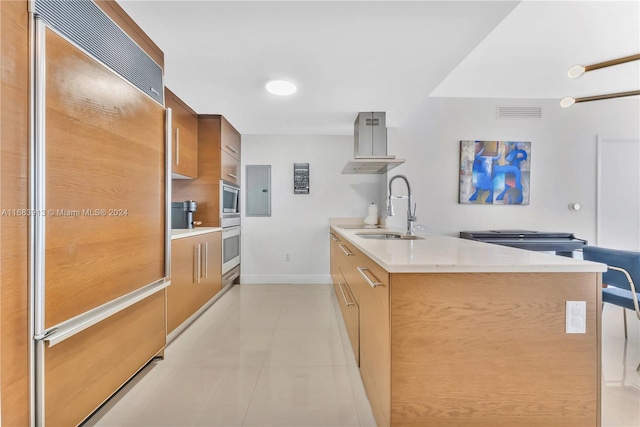 kitchen featuring sink, island exhaust hood, built in appliances, light stone counters, and light tile patterned floors