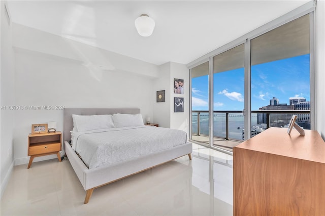 bedroom with a water view, access to outside, and expansive windows