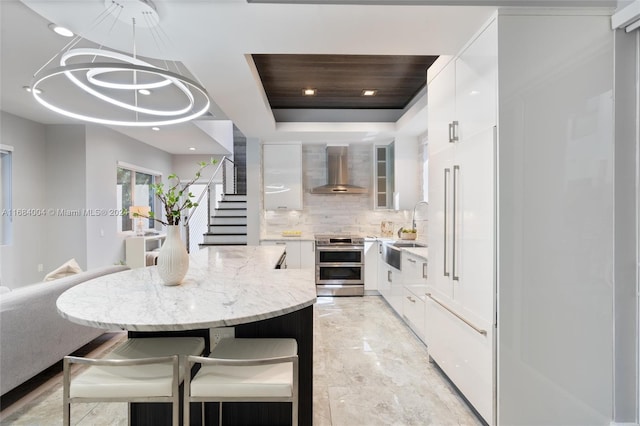 kitchen featuring wall chimney exhaust hood, sink, white cabinetry, stainless steel electric range oven, and tasteful backsplash