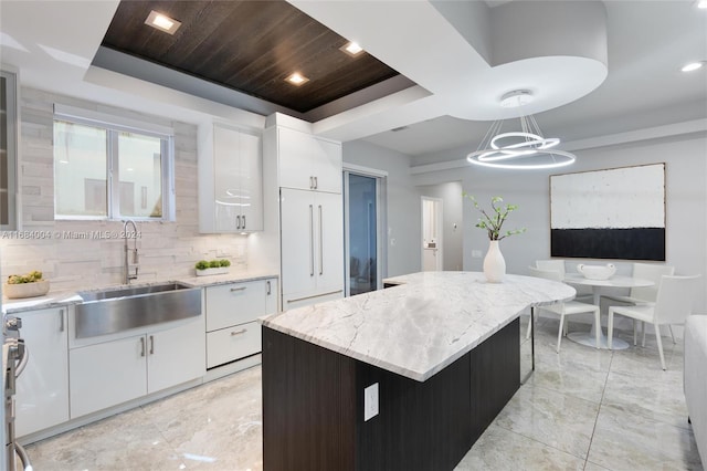 kitchen featuring white cabinets, a center island, hanging light fixtures, and sink