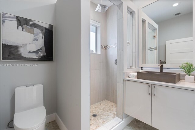 bathroom with vanity, toilet, and tiled shower