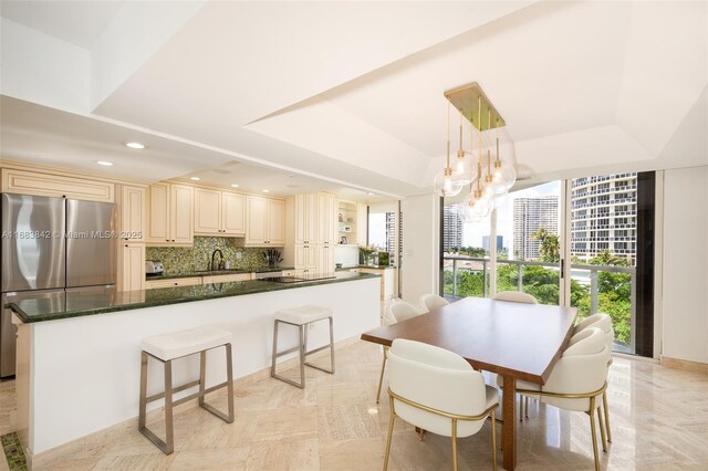 dining area with sink, a notable chandelier, and a tray ceiling