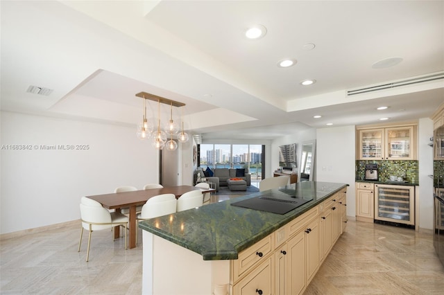 kitchen featuring a center island, a tray ceiling, pendant lighting, black electric stovetop, and beverage cooler