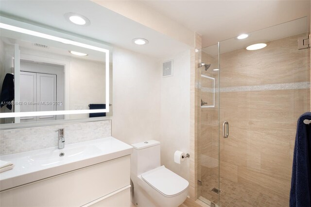 bathroom featuring vanity, backsplash, toilet, and walk in shower