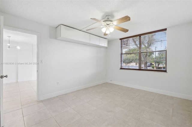 tiled spare room with a textured ceiling and ceiling fan with notable chandelier