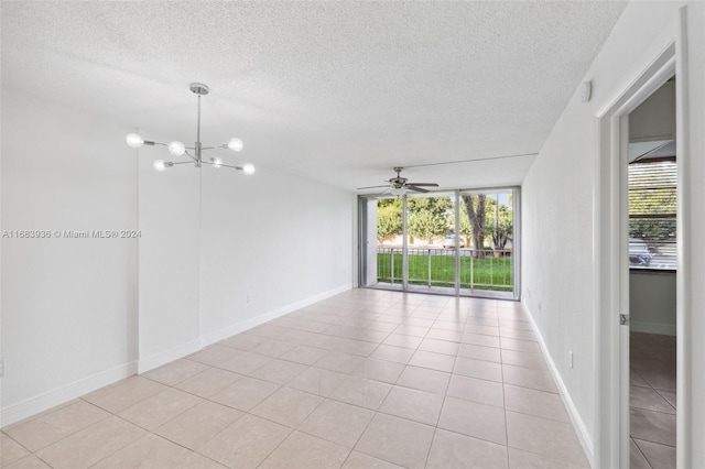 tiled spare room featuring a textured ceiling and ceiling fan with notable chandelier