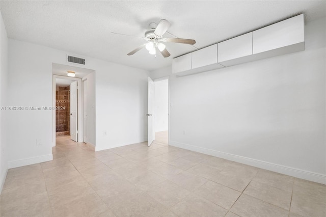 tiled empty room with a textured ceiling and ceiling fan