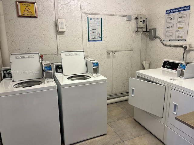 laundry area with washing machine and clothes dryer and light tile patterned floors