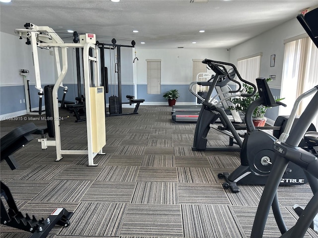 exercise room with a textured ceiling and dark carpet