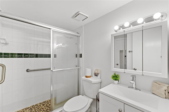 bathroom with toilet, a shower with shower door, and vanity