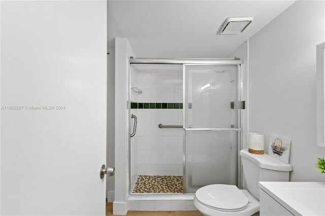 bathroom featuring toilet, vanity, and a shower with door