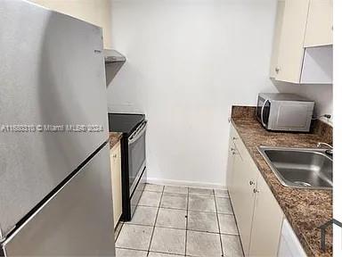 kitchen featuring appliances with stainless steel finishes, white cabinets, sink, and light tile patterned floors