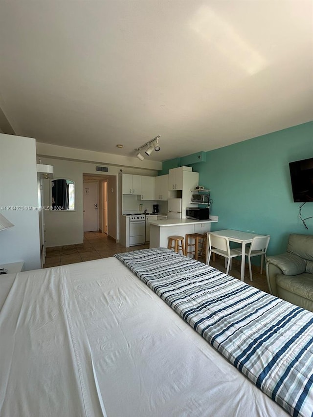 tiled bedroom featuring rail lighting and white refrigerator