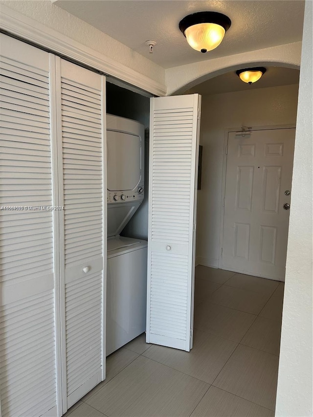 laundry room with stacked washer / drying machine and light tile patterned flooring