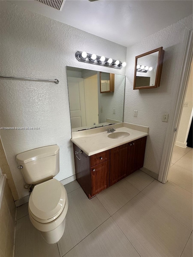 bathroom featuring vanity, toilet, and tile patterned flooring