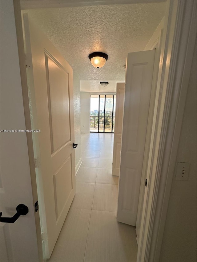 hallway featuring light tile patterned flooring and a textured ceiling