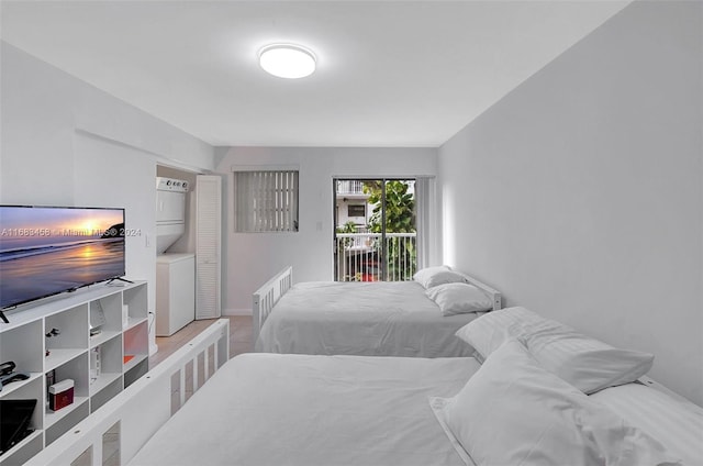 bedroom with stacked washer / dryer, light hardwood / wood-style flooring, and access to exterior