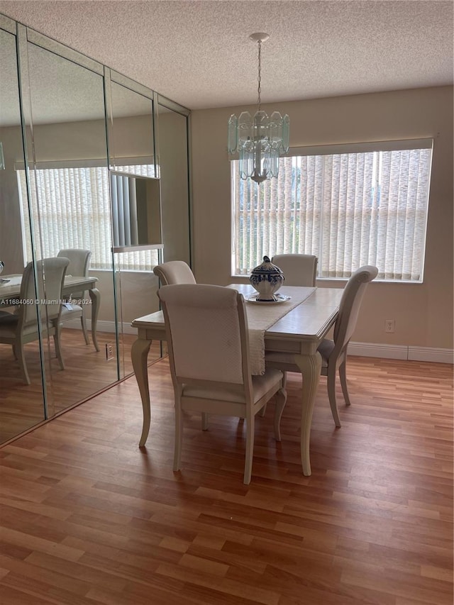 dining area with a textured ceiling, hardwood / wood-style flooring, and a chandelier