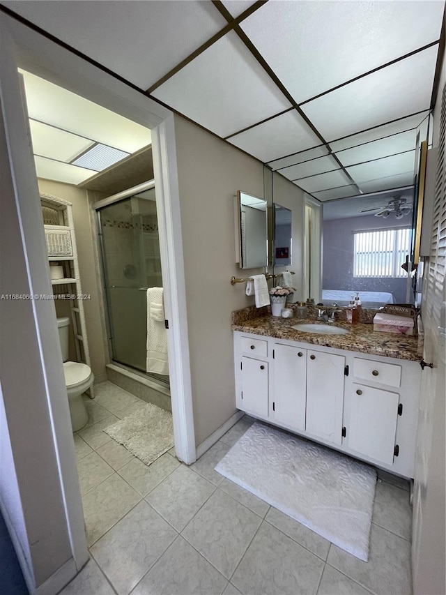 bathroom featuring tile patterned floors, toilet, a shower with shower door, vanity, and ceiling fan