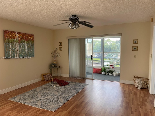 interior space with ceiling fan, wood-type flooring, and a textured ceiling