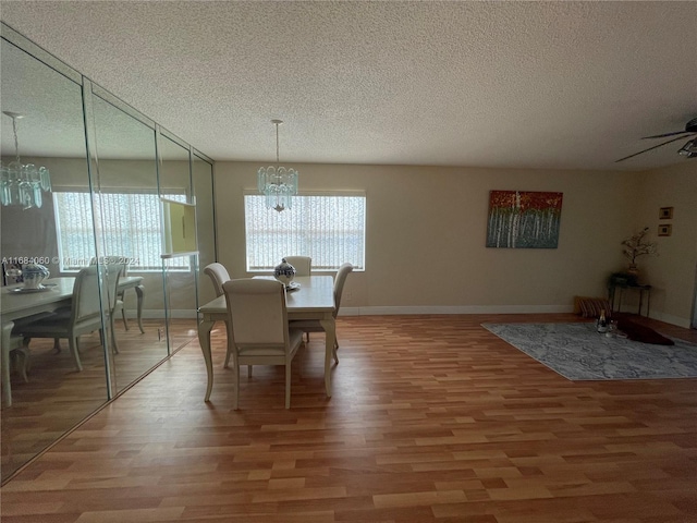 dining room with a textured ceiling, hardwood / wood-style flooring, and ceiling fan with notable chandelier