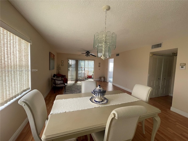 dining room with a textured ceiling, ceiling fan with notable chandelier, and dark hardwood / wood-style flooring