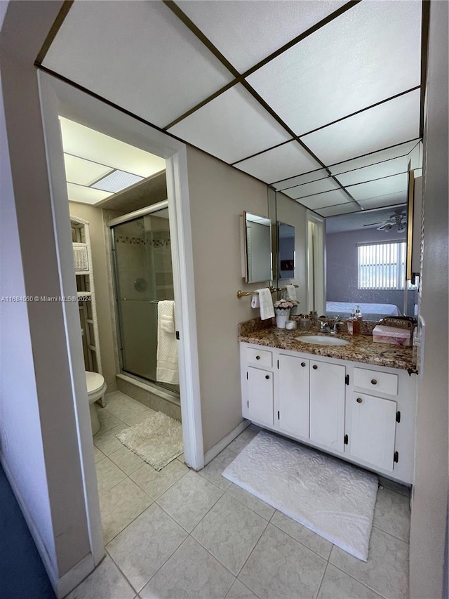 bathroom with a shower with shower door, toilet, ceiling fan, tile patterned floors, and vanity