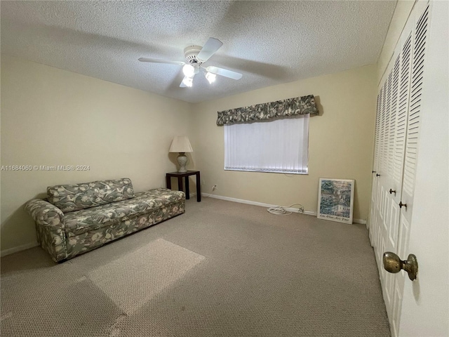 sitting room featuring ceiling fan, a textured ceiling, and carpet floors