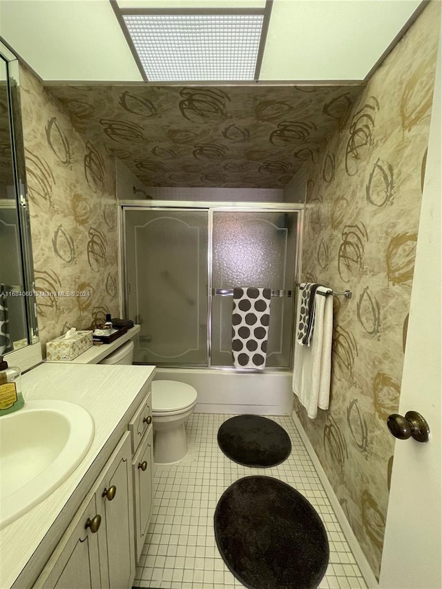 full bathroom featuring toilet, bath / shower combo with glass door, vanity, and tile patterned flooring