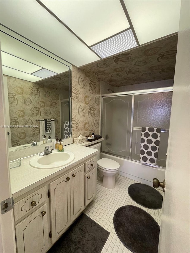 full bathroom with vanity, combined bath / shower with glass door, toilet, and tile patterned flooring