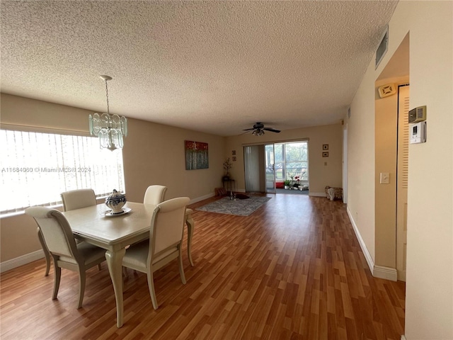 dining space with hardwood / wood-style flooring, a textured ceiling, and ceiling fan with notable chandelier